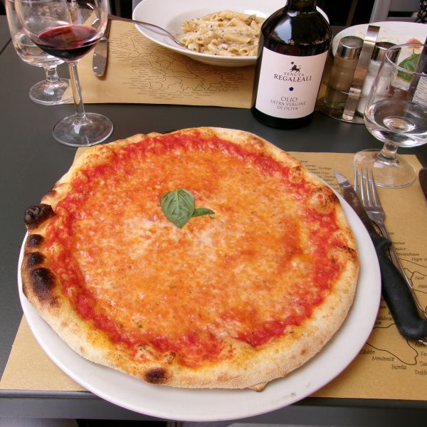 Pizza on a table with some wine and olio