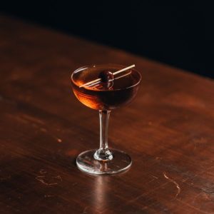 Black Manhattan in a coupe glass on a table